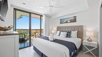 Una habitación de hotel moderna con una cama grande, un balcón con vistas, un ventilador de techo y un cuadro en la pared.