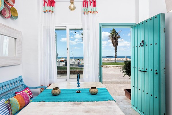 Una stanza con vista mare, una porta color acquamarina e un divano blu con cuscini colorati.