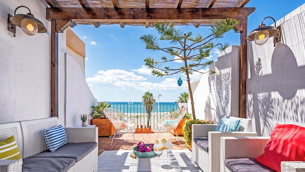 Un espacio al aire libre con mobiliario de mimbre y vistas al mar.