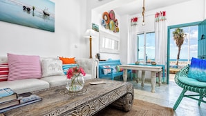 Una sala de estar con sofá, mesa de centro y vista a la playa.