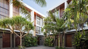 A courtyard with a modern building, large windows, and lush greenery. - Coco Jungle Canggu Villas by Nagisa Bali (Canggu)