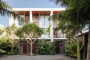 A modern building with a courtyard, featuring a mix of tropical plants and a paved walkway. - Coco Jungle Canggu Villas by Nagisa Bali (Canggu)