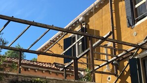 A building with a yellow facade, a brick lower section, and a wooden structure in the foreground. - Painters House Biennale Arsenale (Venice)