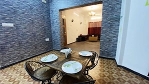 Un comedor con pared de piedra, una mesa de madera con platos blancos y sillas negras.