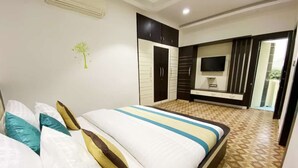 Habitación de hotel con cama, armario, televisión y baño visible a través de una puerta abierta.
