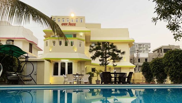 Un hotel con piscina, mobiliario exterior y un cartel en idioma local.