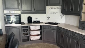 Una cocina con gabinetes gris oscuro, horno empotrado, tostadora y salpicadero con normas para la cocina.