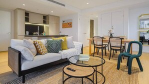 A modern living room with a sofa, coffee table, and dining area.