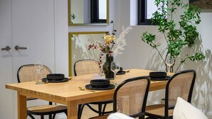 A dining area with a wooden table, black chairs, and a vase with flowers.