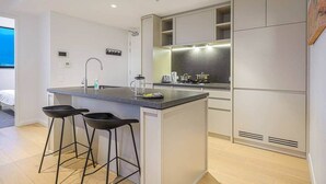 A modern kitchen with a central island, bar stools, and built-in appliances.