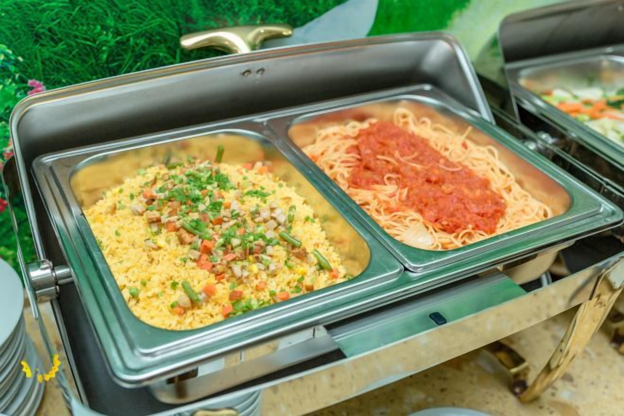 A buffet with two serving dishes, one with a yellowish mixture and the other with spaghetti and tomato sauce.
