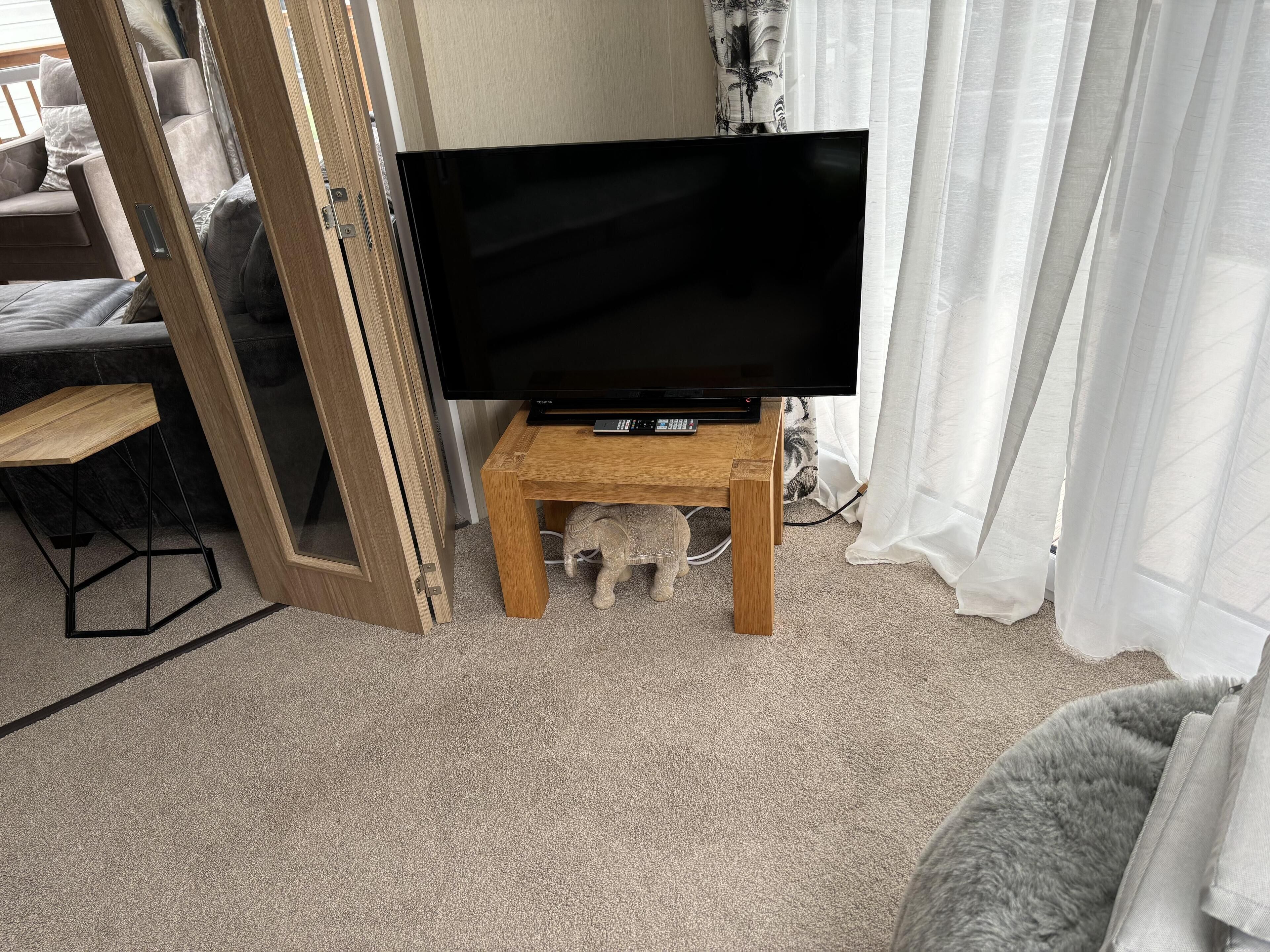 A living room with a television on a wooden stand, a small elephant figurine, and a partially open door.