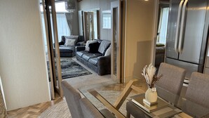 Un salon moderne avec une table basse en verre, un canapé en cuir et un coin repas comprenant une table et des chaises en verre.