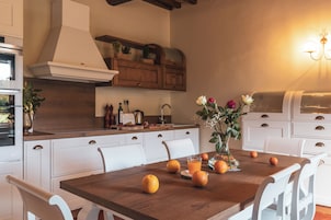 Una cocina moderna con armarios blancos, una mesa de comedor de madera y un jarrón con flores.