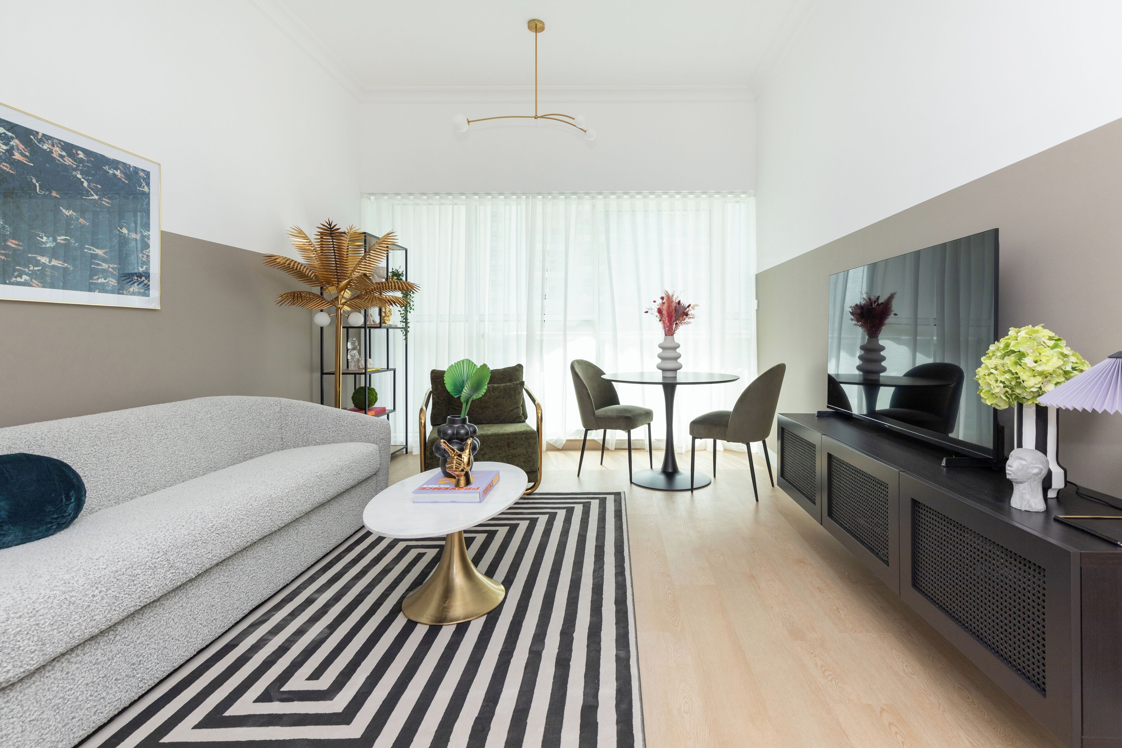 A modern living room with a sofa, a coffee table, a TV, and a dining area with chairs and a table.