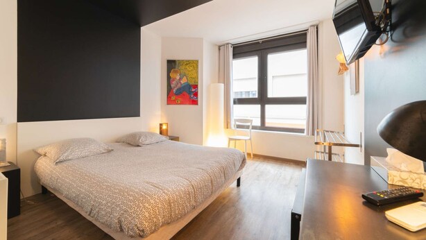 Ein modernes Schlafzimmer mit Bett, Schreibtisch, Fernseher und einem Fenster mit Vorhängen.