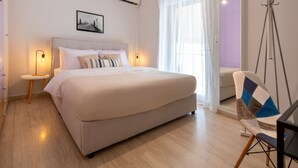 Ein Schlafzimmer mit Bett, Nachttischen, einem Sessel und einem Fenster mit Vorhängen.
