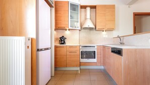 Eine kleine Küche mit Holzschränken, einem eingebauten Backofen und einem Geschirrspüler.