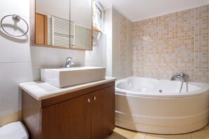 A modern bathroom with a freestanding bathtub, a vanity with a sink, and a large mirror.