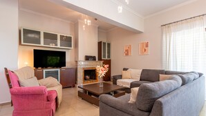 Ein Wohnzimmer mit Fernseher, Kamin, Sofa und Sesseln.
