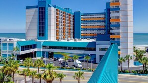 Un hôtel moderne à la façade bleue et blanche remarquable, doté de nombreux balcons et offrant une vue sur la plage.