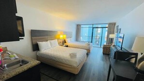 A hotel room with a large bed, a desk, a chair, a sink, and a balcony with a view. - LA82 Beautiful Studio on the beach + pool+ hot tub (Myrtle Beach)