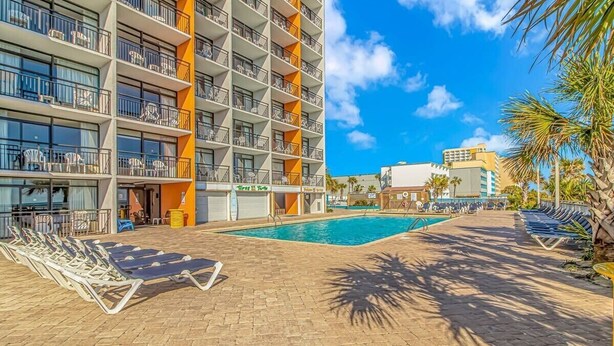 A hotel with a pool area, multiple balconies, and a clear blue sky. - LA82 Beautiful Studio on the beach + pool+ hot tub (Myrtle Beach)