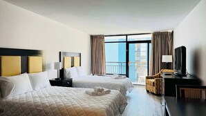 A hotel room with two beds, a desk with a computer, a chair, and a balcony with curtains. - LA11 Great condo right on the beach+pool+Hot tub (Myrtle Beach)
