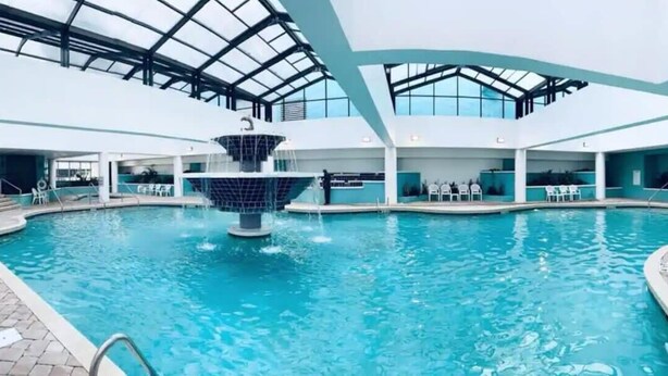 An indoor swimming pool with a central fountain, surrounded by lounge chairs and a glass ceiling. - LA11 Great condo right on the beach+pool+Hot tub (Myrtle Beach)