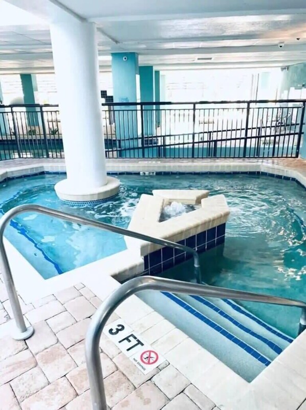 Una piscina interior con un jacuzzi, un indicador de profundidad de 3 pies y un letrero que prohíbe los saltos.