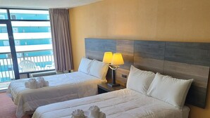 A hotel room with two beds, a nightstand with a lamp, and a view of a building through large windows. - LA12 Wonderful condo on the beach + pool + Hot tub (Myrtle Beach)