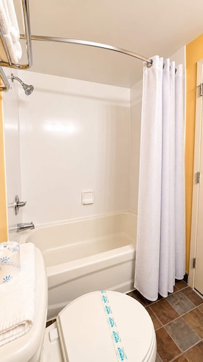 A bathroom with a bathtub, toilet, and shower curtain.