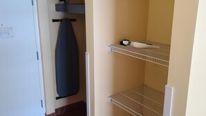 A compact room with a white refrigerator, a small ironing board, and a metal shelf unit. - LA12 Wonderful condo on the beach + pool + Hot tub (Myrtle Beach)
