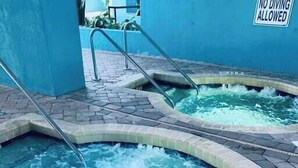 Ein Whirlpool mit einem Schild, auf dem 'Tauchen verboten' steht, umgeben von einer gefliesten Terrasse.