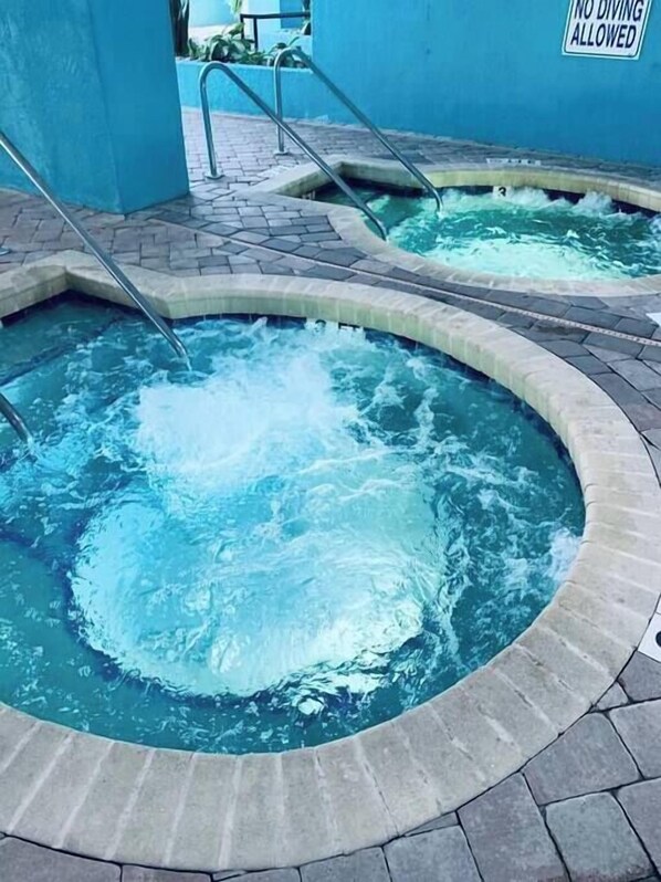 Een hottub met een bordje 'NO DIVING ALLOWED', omgeven door een betegeld terras.