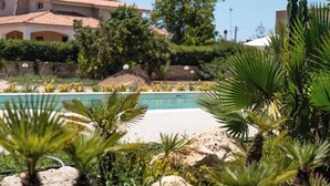 A pool area with palm trees and a building in the background.
