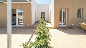 A modern building with a central corridor, large windows, and a wooden floor.