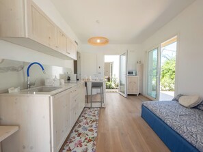 Enjoy a compact yet functional stay with a kitchenette, dining area, and bedroom featuring a large window with an outdoor view.