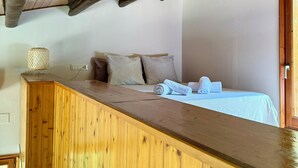 A hotel room with a wooden desk, a bed with beige bedding, and a lamp on the desk. - Racons del Pedraforca (Saldes)