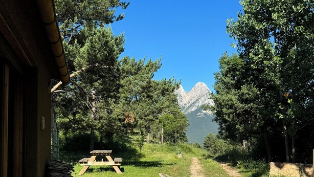 A rustic cabin with a gravel path leading to a picnic table and a mountain in the background. - Racons del Pedraforca (Saldes)