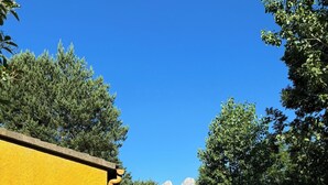 A yellow building with a dirt path leading to a lake and mountains in the distance. - Racons del Pedraforca (Saldes)
