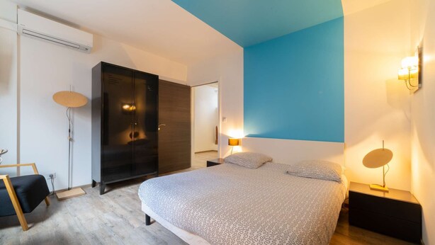 Een slaapkamer met een groot bed, een kledingkast, een bureau en een stoel.