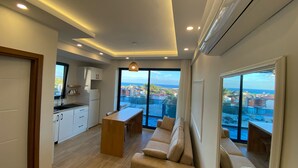 A modern living room with a sofa, a coffee table, and a view of the sea through large windows. - Atlas homes (Demre)