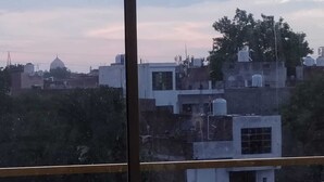 Visão através de uma janela de um horizonte urbano com edifícios, incluindo uma estrutura em forma de cúpula.