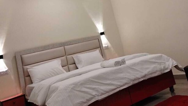 Quarto com cama, mesas de cabeceira, tapete vermelho e ventilador de teto.