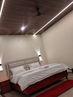 A bedroom with a bed, nightstands, a red rug, and a ceiling fan. -  Sunrise Homestay Agra-Rooftop View Taj Mahal (Agra)