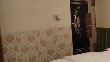 Una habitación de hotel con una cama, una alfombra roja, aire acondicionado instalado en la pared y una puerta decorativa.