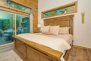 A bedroom with a large bed, wooden headboard, and a view of the outdoors through a sliding glass door.