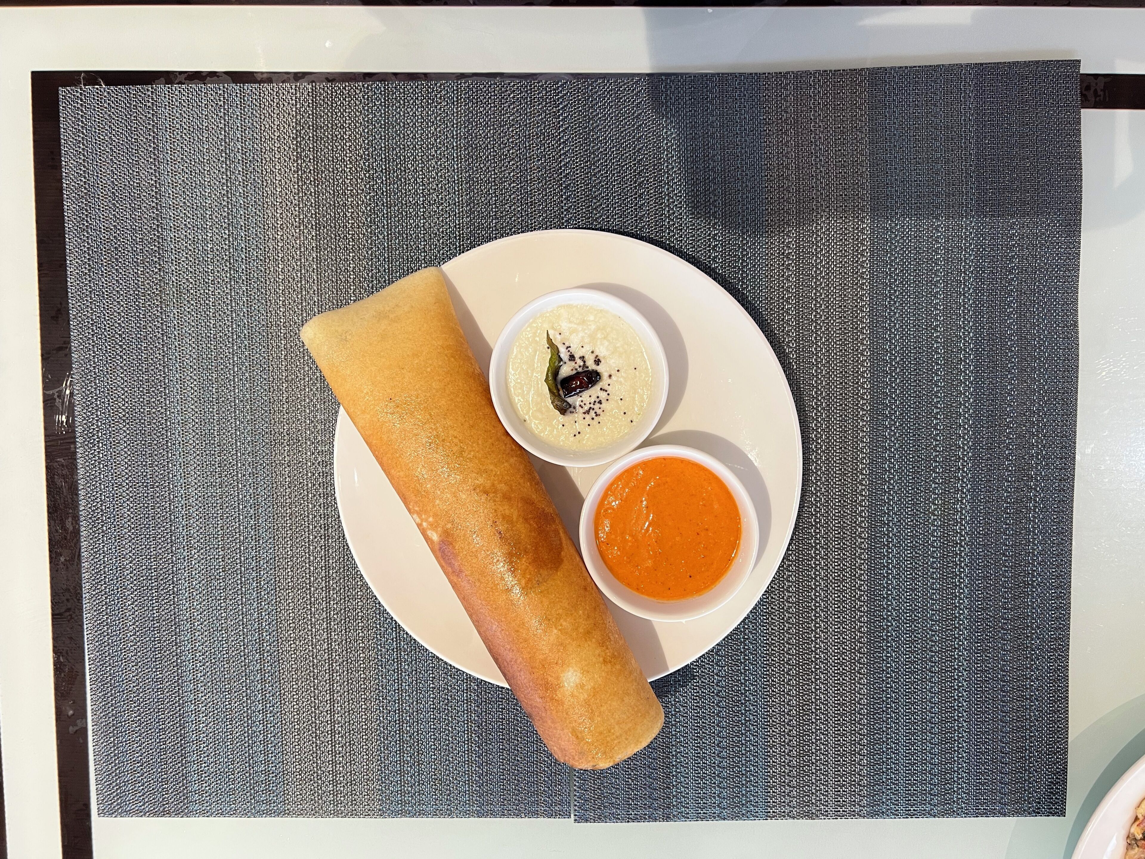 A plate with a rolled food item and two small bowls of sauce.