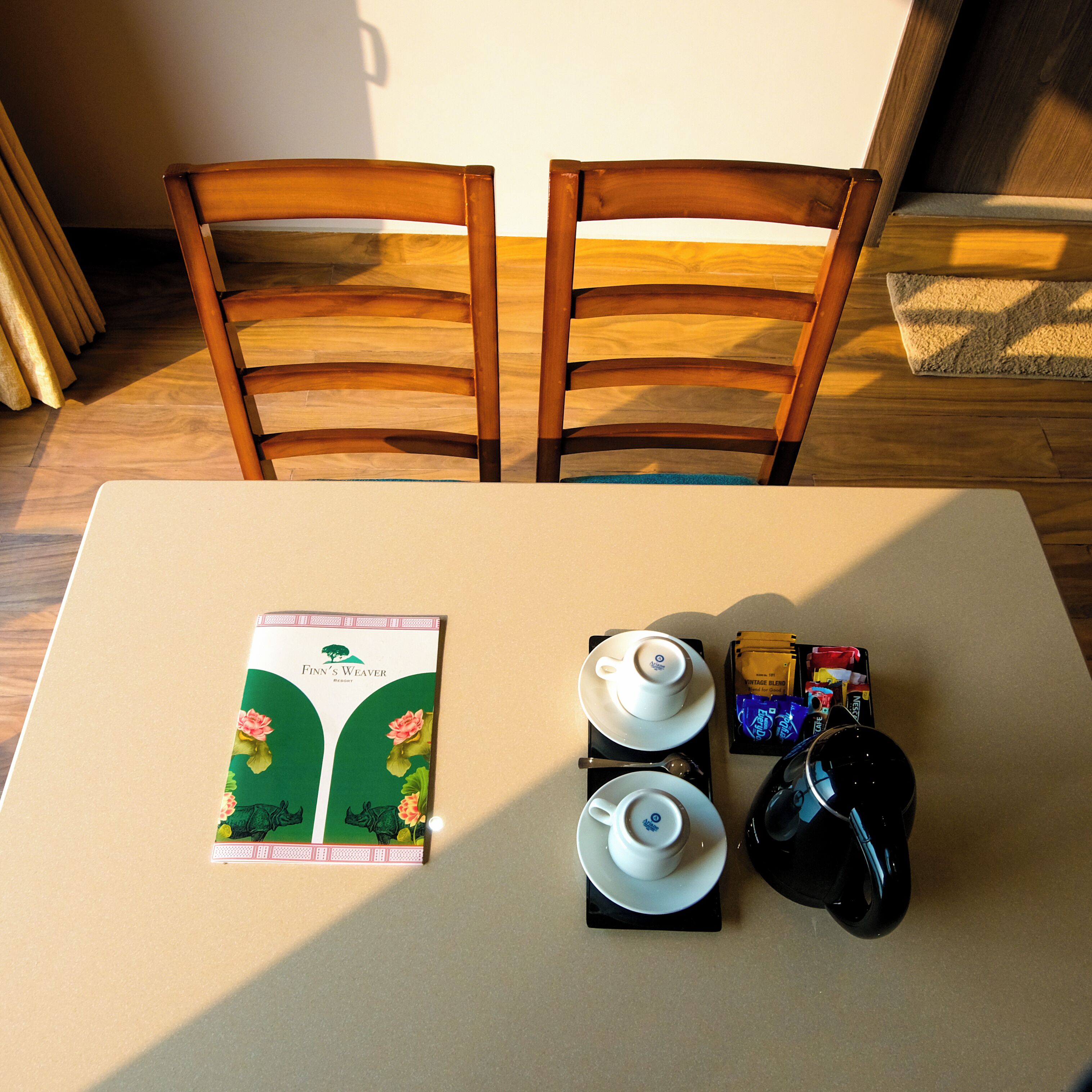 A table with a book, teacups, a teapot, and a teapot lid.